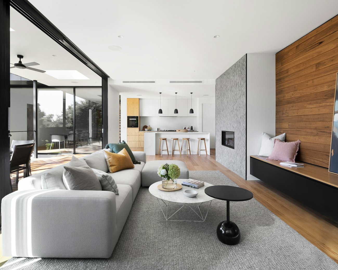 A modern open-plan living room with a wood feature wall, designed and installed by NESTORA